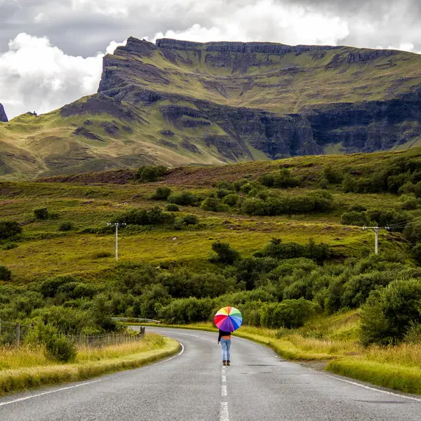 妇女的后方看法与伞在乡村路 苏格兰 — 图库照片