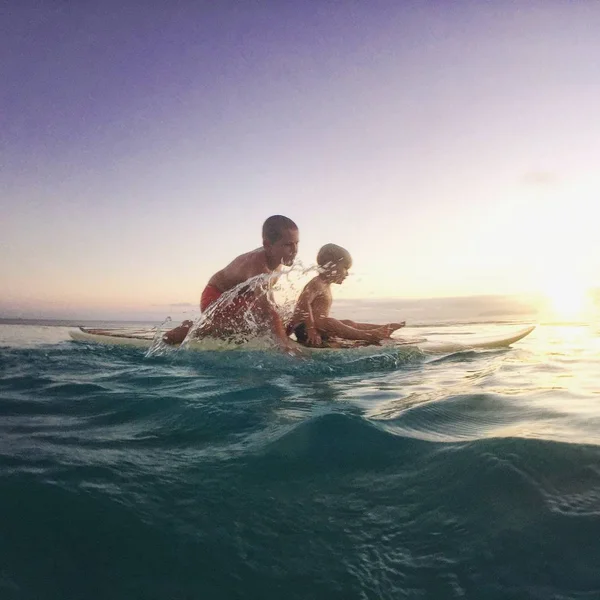 Мальчики гребут на доске для серфинга — стоковое фото