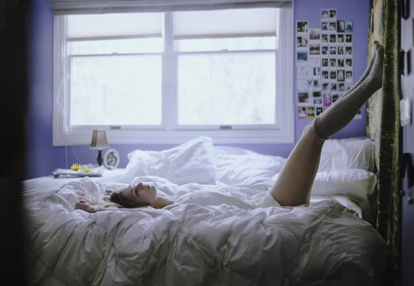 Junge Frau liegt auf ihrem Bett — Stockfoto