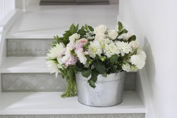 Bucket of beautiful delicate cut flowers on steps — Stock Photo