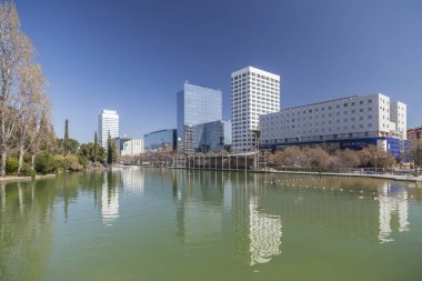 Modern buildings and reflection in pond in Eix Macia area, Sabadell, province Barcelona, Catalonia. clipart