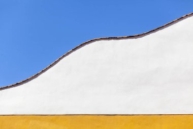 Duvar rengi beyaz ve sarı kavisli ve mavi gökyüzü.
