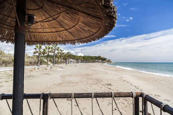 Středozemní moře, jarní slunečný den, pláž a deštník terasa bar, Costa Dorada, Katalánsko, Španělsko. — Stock fotografie