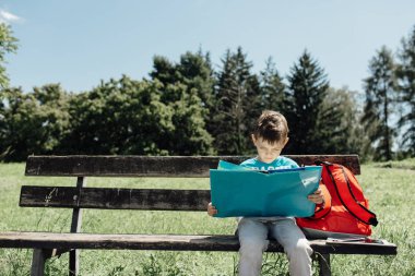 Yalnız bir bankta oturan ve bir kitap okuma öğrenci