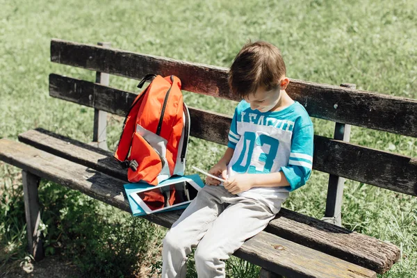Iskolás bevétel egy alkalom, egy padon, és játék-val egy mobil — Stock Fotó