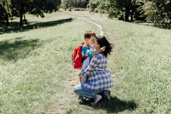 Weinig schooljongen zoenen en knuffelen zijn afscheid van de moeder aan haar — Stockfoto