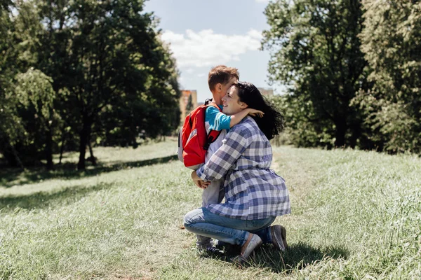 Mamma kramar hennes son och säga adjö till honom på väg till skolan — Stockfoto