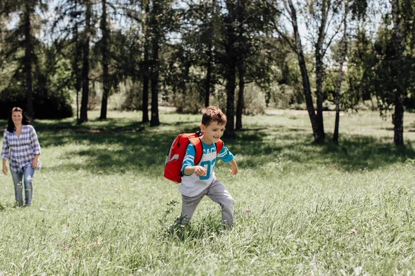 Happy schoolboy on his way to school running away from his mother