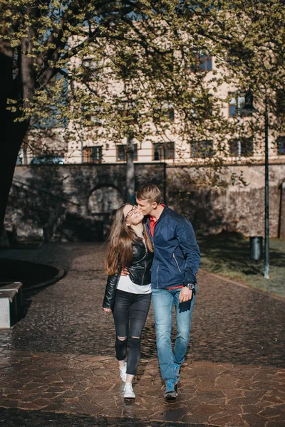 Vista frontal de um jovem casal abraçando e andando na rua chuvosa — Fotografia de Stock