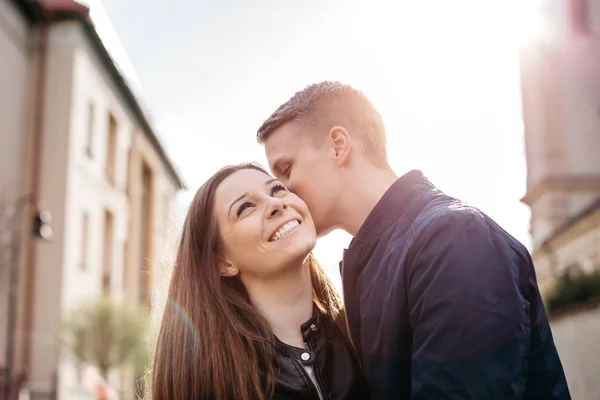 En pojkvän som viskar i hans flickvänner öra dejtande i staden — Stockfoto