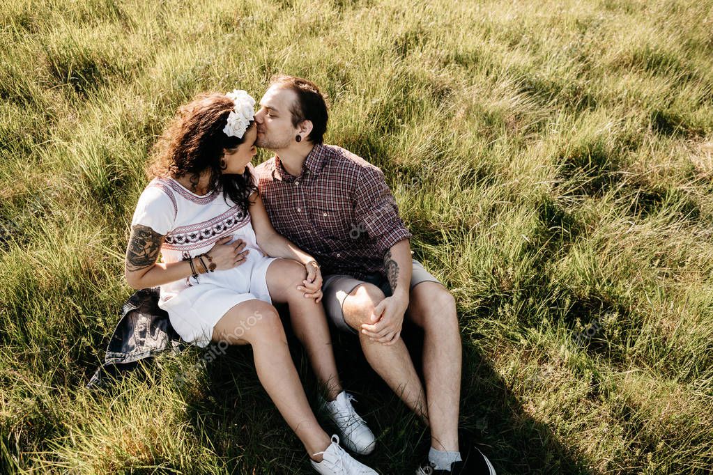 Portrait of a loving pregnant couple sitting on grass