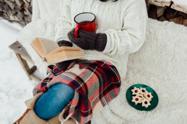 Kadın kitap okuyor ve çay içiyor. 