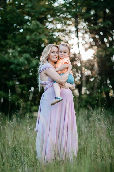 Een zwangere vrouw met haar jonge zoon in haar armen. — Stockfoto
