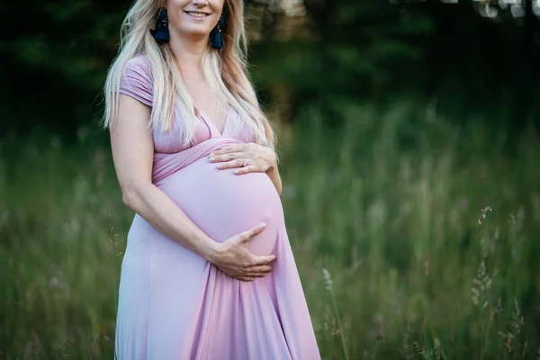 Uma imagem recortada de uma mulher grávida sorridente na natureza . — Fotografia de Stock