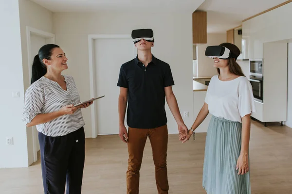 Yeni dairede VR kulaklık takan genç çiftli emlakçı..