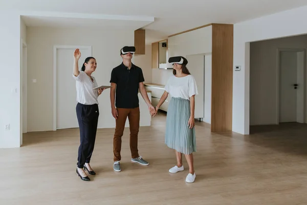 Yeni dairede VR kulaklık takan genç çiftli emlakçı..