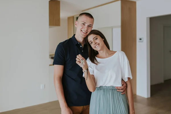 Glada unga par i nytt hus med nycklar. — Stockfoto
