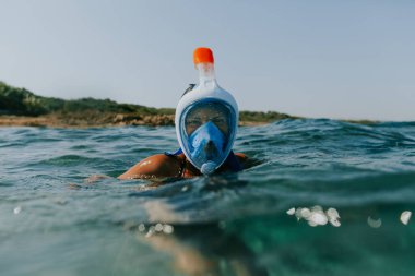Woman swimming at water surface wearing snorkel mask.