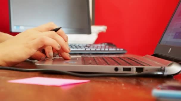 Femaile palce z ładny Manicure z szarego paznokcie są dotykając Touchpad laptopa i przytrzymując pióro, czerwone tło, z bliska — Wideo stockowe
