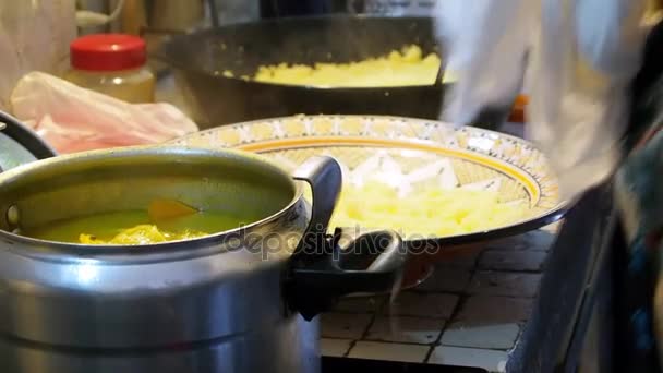 摩洛哥妇女是烹饪传统摩洛哥菜蒸粗麦粉与肉和蔬菜。厨师从一壶给麦粉板用一把勺子和手。摩洛哥的食物。关闭。丹吉尔，摩洛哥. 免版税图库视频