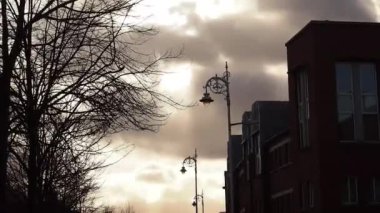 Daireli ev, ağaç yaprakları ve Lampposts ile gizemli günbatımı renkli gökyüzü arka plan ile. Bulutlar rüzgarla hareket. Gece şehir. Dublin, İrlanda.