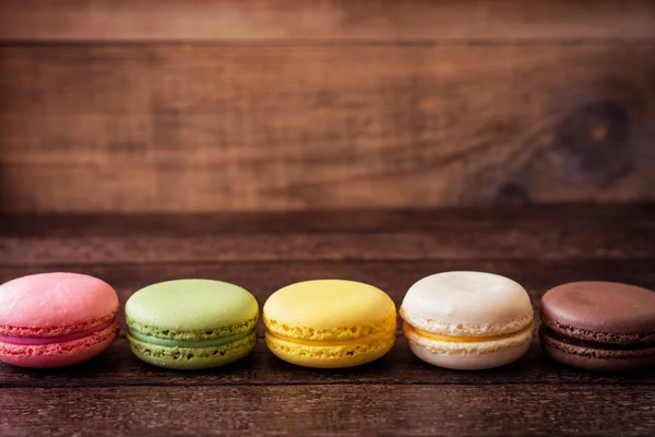 Macarons coloridos em fundo de madeira escura — Fotografia de Stock