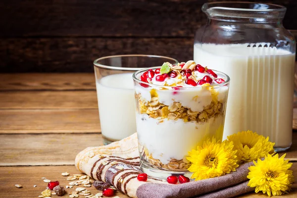 Gezond ontbijt met yoghurt, muesli en granaatappel zaden in glas op houten achtergrond — Stockfoto