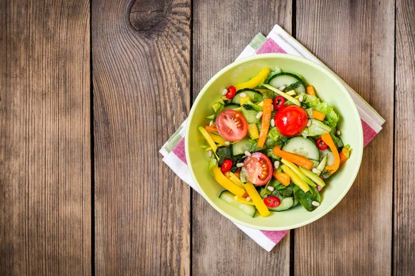 Ensalada fresca con verduras, verduras y piñones sobre fondo de madera — Foto de Stock