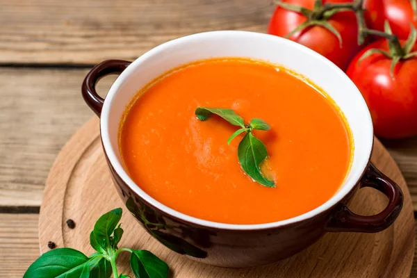 Tomatsoppa i keramikskål på trä bakgrund. — Stockfoto