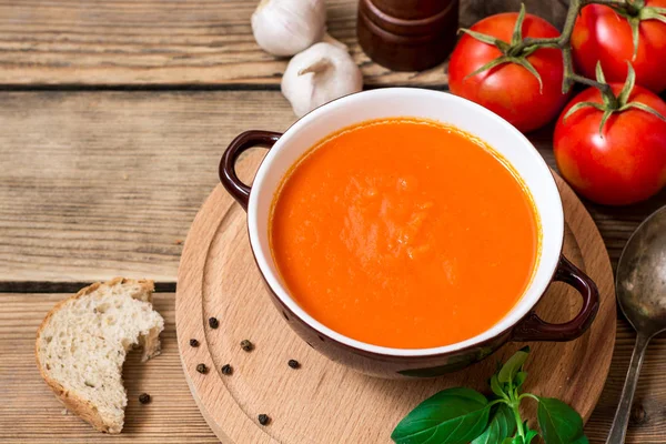 Tomatsoppa i keramikskål på trä bakgrund. — Stockfoto