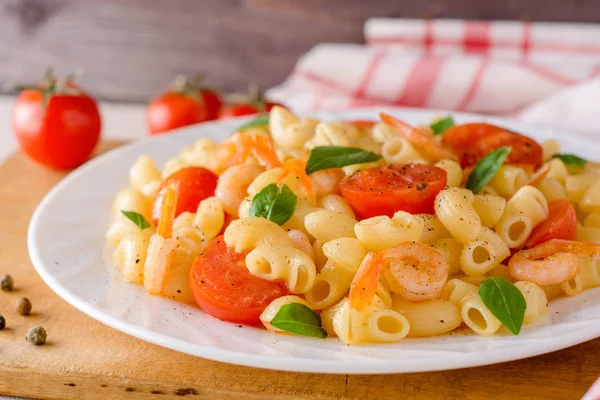 Pasta con gambas, tomates cherry y albahaca en plato blanco . — Foto de Stock