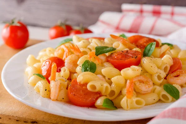 Pasta con gambas, tomates cherry y albahaca en plato blanco . — Foto de Stock