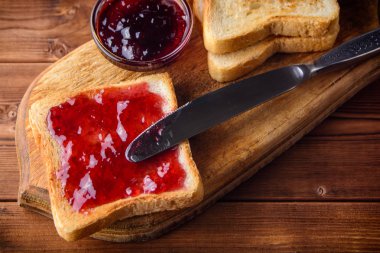 Rustik ahşap kesme tahtası üzerinde vişne reçelli tost.