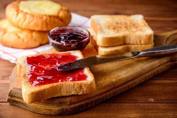 ขนมปังปิ้งกับแยมเชอร์รี่บนกระดานตัดไม้ชนบท . — ภาพถ่ายสต็อก
