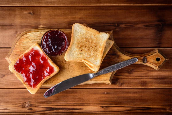 Torrada com geléia de cereja em tábua de corte de madeira rústica . — Fotografia de Stock