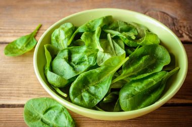 Yıkanmış taze ıspanak kapta rustik ahşap masanın üzerine bırakır..