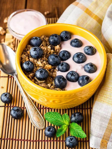 格兰诺拉麦片，蓝莓和酸奶在木制的桌子上的黄色碗. — 图库照片