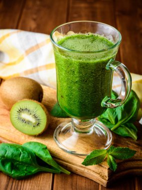 Ispanak ve kivi rustik ahşap zemin üzerine cam ile sağlıklı yeşil smoothie.