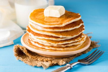 Tereyağı ve mavi ahşap masa üzerinde ballı krep.