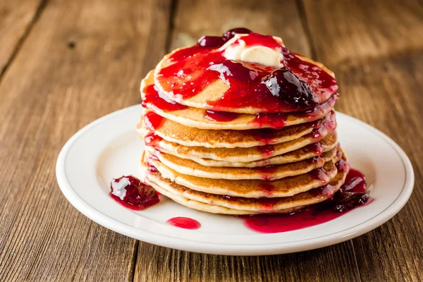 Pancakes with butter and jam on wooden table. — Stock Photo, Image