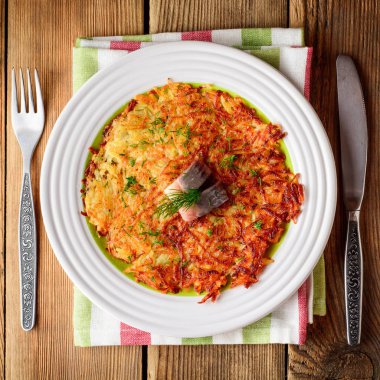 Patates rosti ile dereotu ve ahşap masa tabağa tuzlanmış ringa.