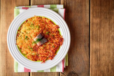 Patates rosti ile dereotu ve ahşap masa tabağa tuzlanmış ringa.