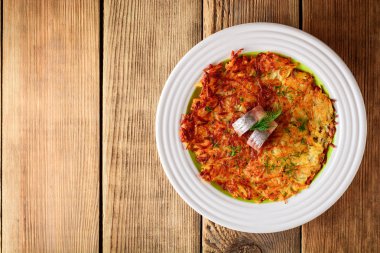 Patates rosti ile dereotu ve ahşap masa tabağa tuzlanmış ringa.