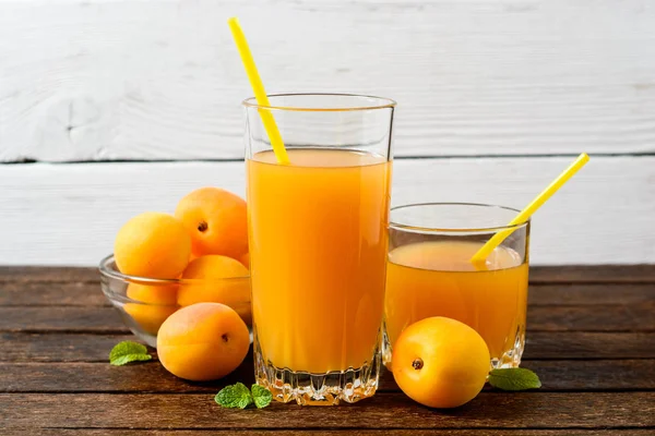 Свежий абрикосовый сок и абрикосы на деревянном столе . — стоковое фото