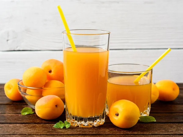 Свежий абрикосовый сок и абрикосы на деревянном столе . — стоковое фото