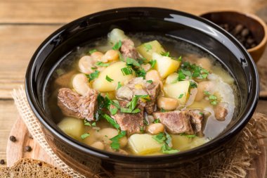 İşkembe çorbası ile patates, fasulye ve pırasa taş zemin üzerine seramik kase.