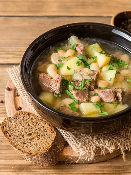 Beef soup with potatoes, beans and leeks in ceramic bowl on stone background. — Stock Photo, Image