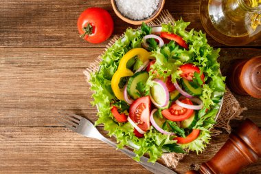 Ahşap masa üzerinde yeşillikleri ile taze sebze salatası.