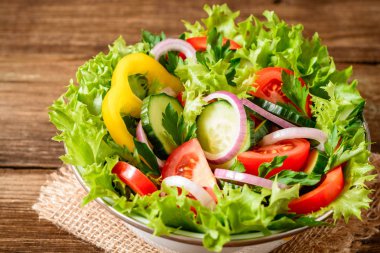Ahşap masa üzerinde yeşillikleri ile taze sebze salatası.