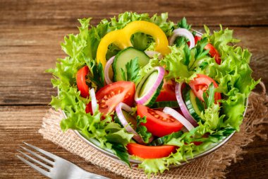 Ahşap masa üzerinde yeşillikleri ile taze sebze salatası.